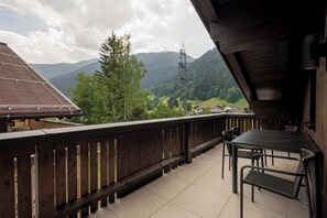 Ein Balkon mit Blick auf Berge, einem Tisch und Stühlen.