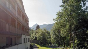 Ein mehrstöckiges Gebäude mit Balkonen, einem begrünten Innenhof und Bergblick.