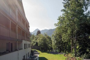 Ein mehrstöckiges Gebäude mit Balkonen, einem begrünten Innenhof und Bergblick.
