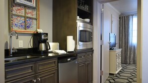 A hotel kitchen with a coffee maker, microwave, and a television in the background.