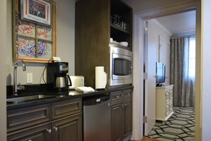 A hotel kitchen with a coffee maker, microwave, and a television in the background.