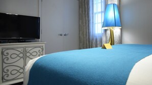 A hotel room with a bed, a television on a cabinet, and a lamp.