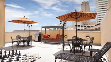 A rooftop terrace with outdoor seating, chess set, and a grill.
