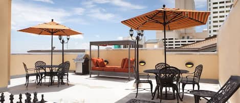 A rooftop terrace with outdoor seating, chess set, and a grill.