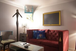 A living room with a red sofa, a blue pillow, a candelabra, and a framed picture on the wall.