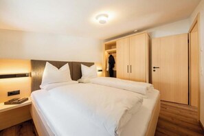 A hotel room with a bed, bedside table, wardrobe, and a ceiling light. - Rovina E3 Apartment (Gaschurn)