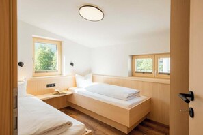 Ein Schlafzimmer mit einem Einzelbett, einem Nachttisch, einem Fenster und einer Tür.