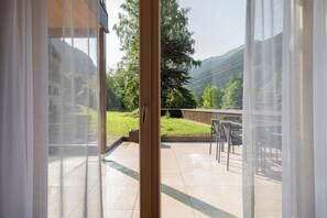 Eine offene Schiebetür führt zu einer Terrasse mit Blick auf eine Berglandschaft.