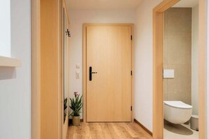 Eine Holztür in einer Diele, mit einem Blumentopf und einem sichtbaren WC im angrenzenden Raum.