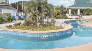 Piscina com borda azulejada, posto de salva-vidas e um edifício com área coberta.
