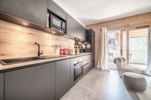 Une cuisine moderne dotée d’un four encastré, d’un four à micro-ondes et d’un pare-feu en bois.