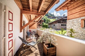 Un balcon en bois offrant une vue sur un bâtiment en pierre et un arbre.