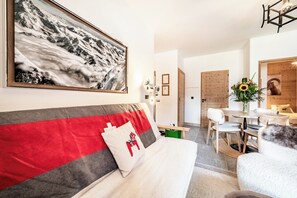 Une chambre d’hôtel moderne dotée d’un grand lit, d’un coin repas et offrant une vue sur les montagnes.