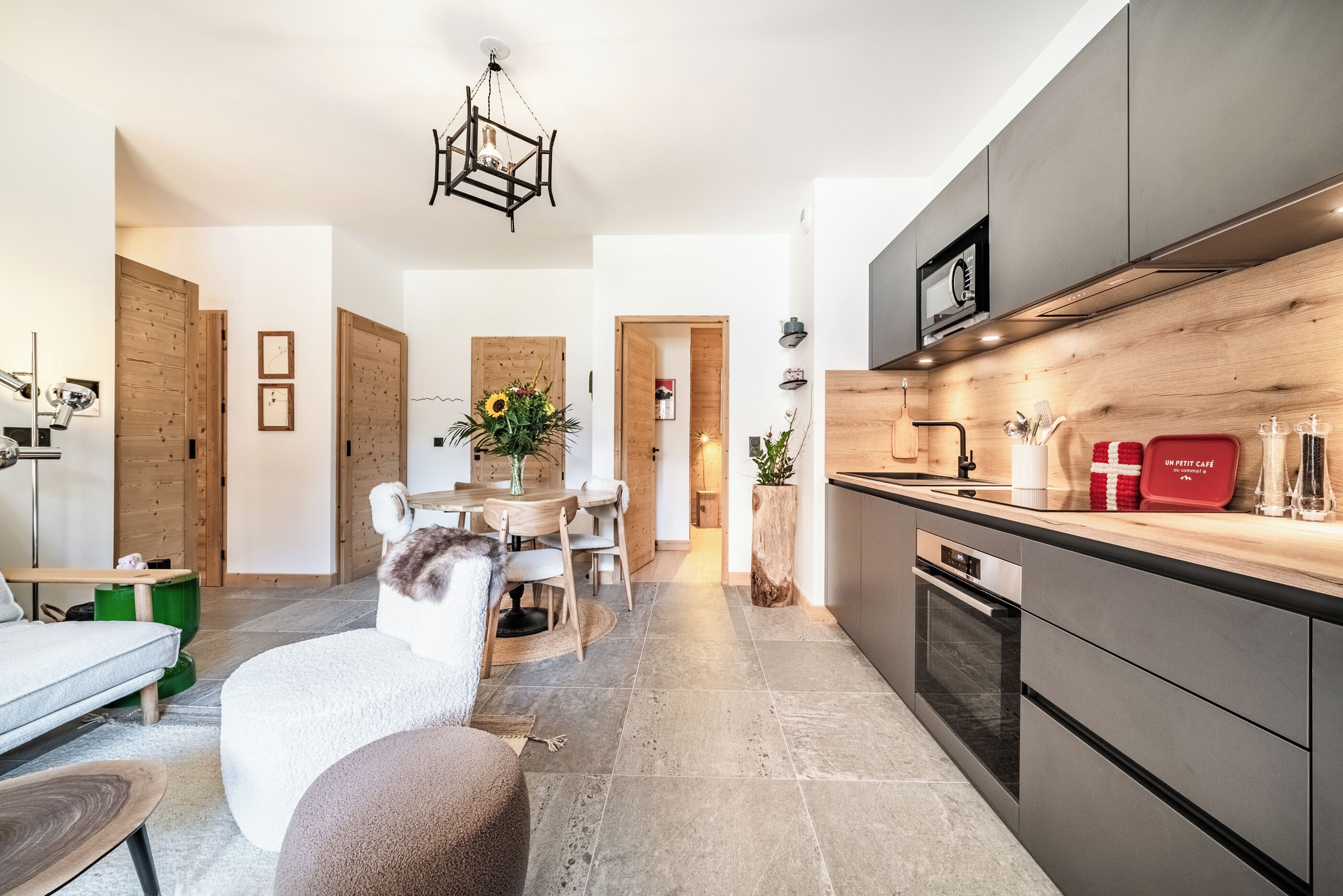 Une cuisine moderne avec des meubles de rangement aux couleurs sombres, un four encastré et un four à micro-ondes.