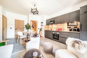 A modern kitchen with dark cabinets, a microwave, and a coffee machine. - Cima – Balcony | Ski Locker | Parking | Morzine (Morzine)