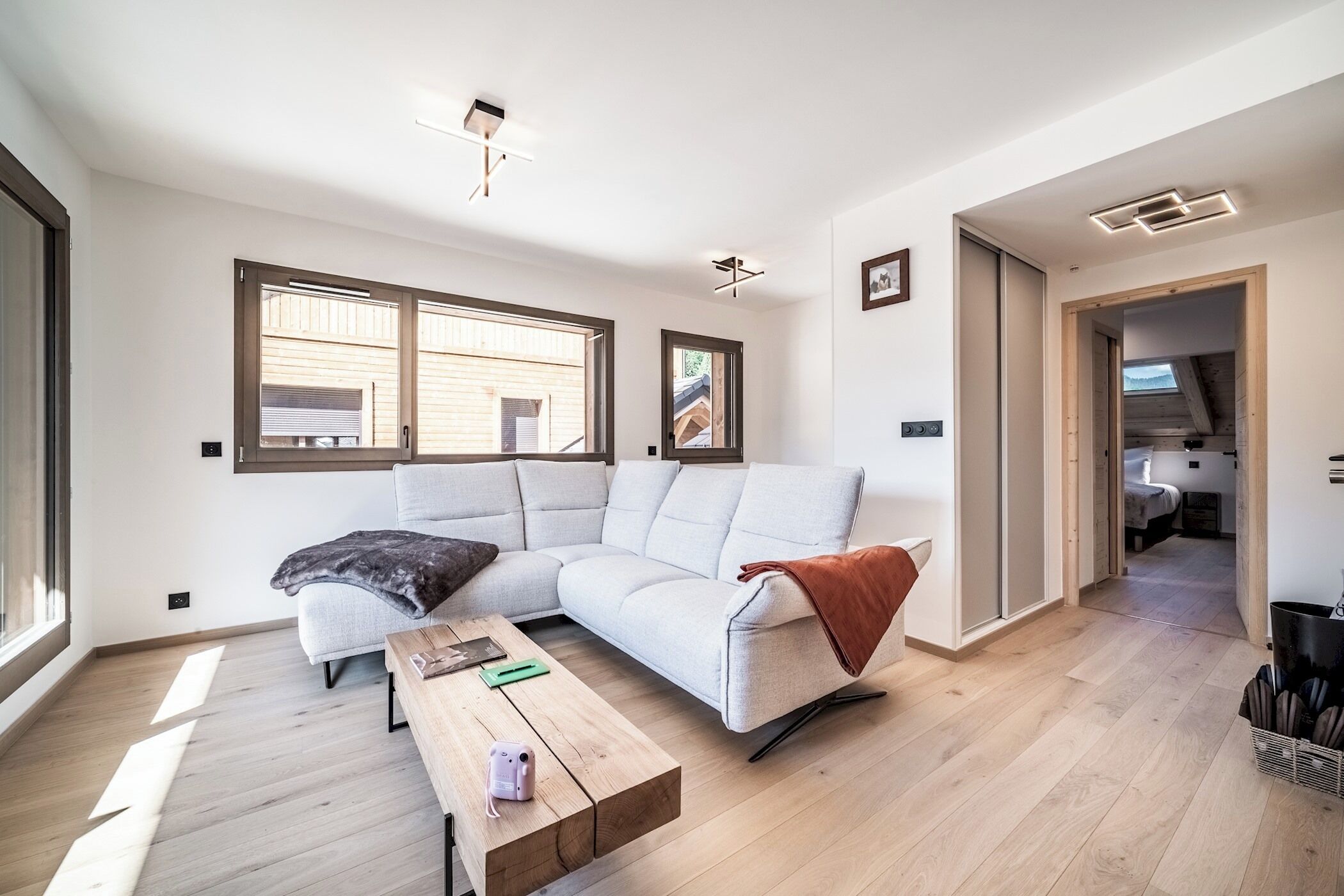 Una sala de estar moderna con un sofá modular, una mesa de centro y vistas al exterior a través de amplios ventanales.