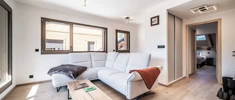 Una sala de estar moderna con un sofá modular, una mesa de centro y vistas al exterior a través de amplios ventanales.