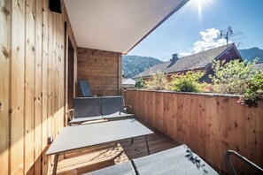 A wooden deck with a view of a traditional building and mountains. - Sequoia – Balcony | Parking | Near Lifts | Morzine (Morzine)