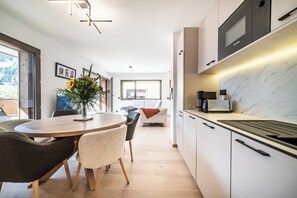 A modern kitchen with white cabinets, a Bosch microwave, and a marble backsplash. - Sequoia – Balcony | Parking | Near Lifts | Morzine (Morzine)
