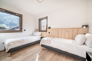 A room with two single beds, wooden headboards, and a large window. - Sequoia – Balcony | Parking | Near Lifts | Morzine (Morzine)