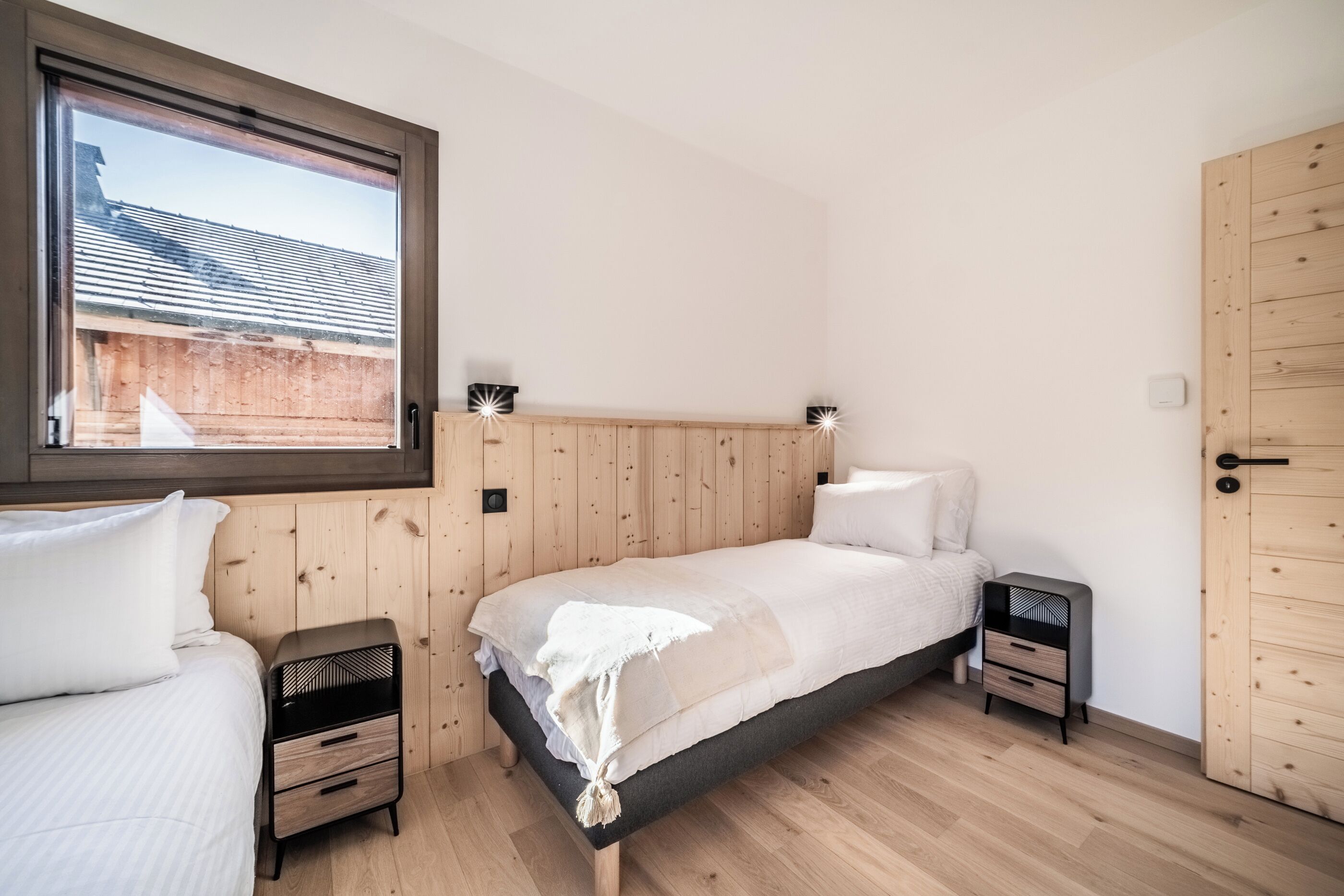 A bedroom with a bed, two nightstands, a window, and a door.