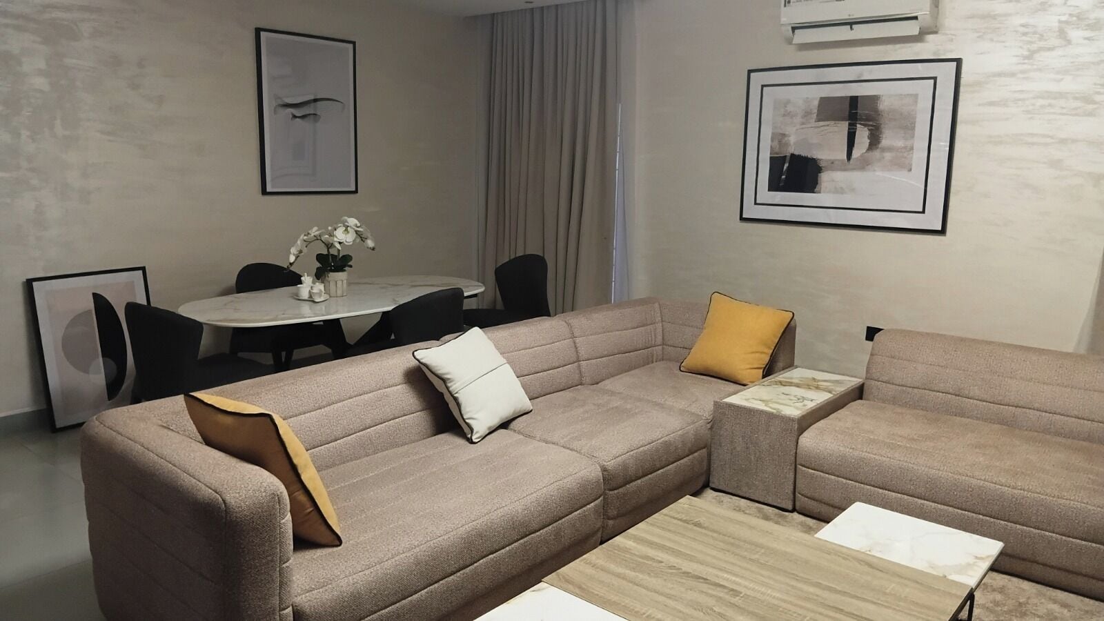 A modern living room with a sectional sofa, a coffee table, and a dining area with a round table and chairs.