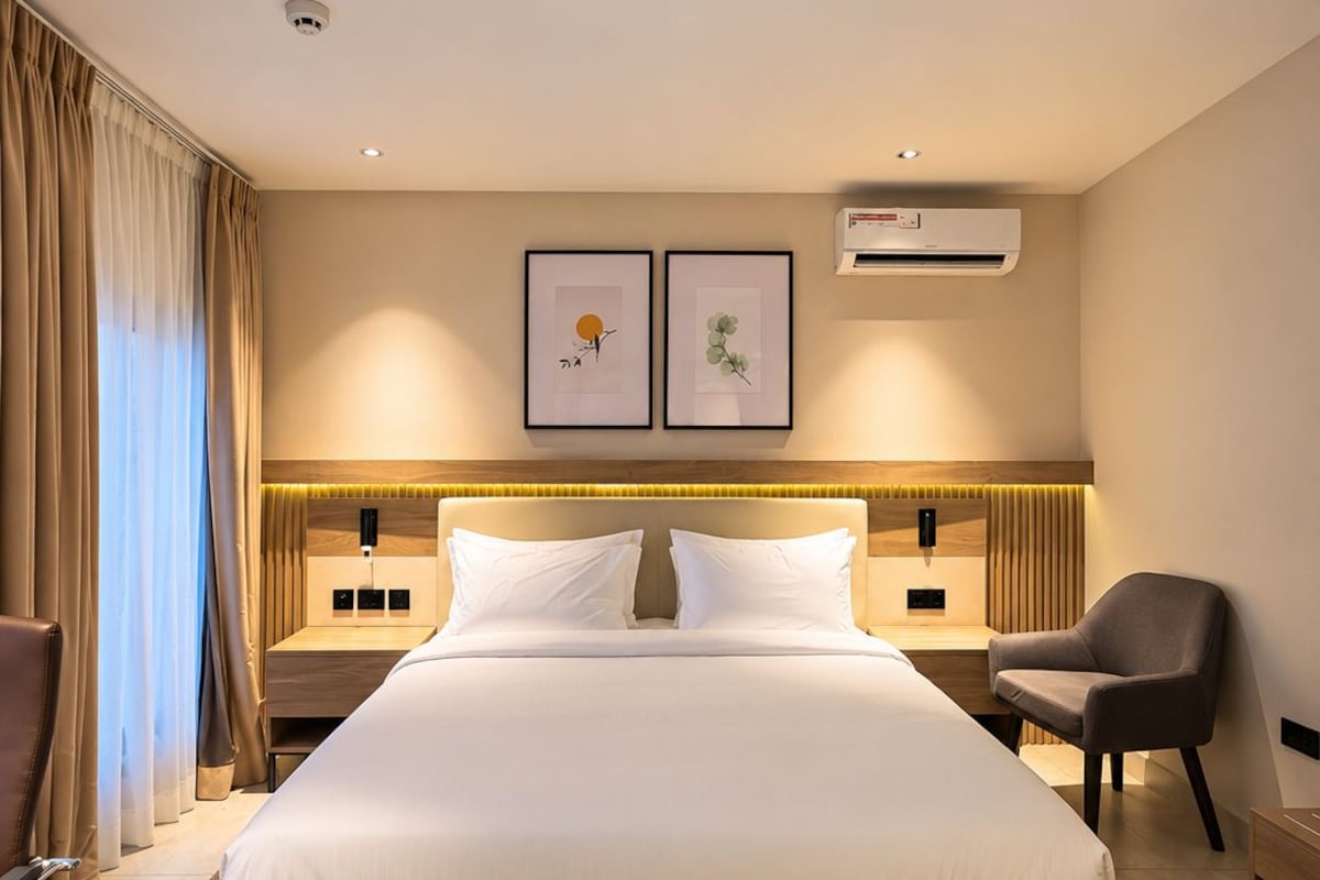 Ein Hotelzimmer mit einem großen Bett, Nachttischen, einem Sessel und Kunstwerken an der Wand.