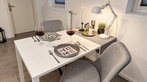 Una mesa de comedor preparada con platos, cubiertos y vasos, con una vela y una lámpara sobre la mesa.