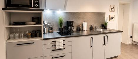 Cocina moderna con microondas, cafetera y lavaplatos.