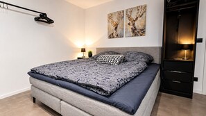 Un dormitori modern amb llit, taules de nit i obra d'art a la paret.