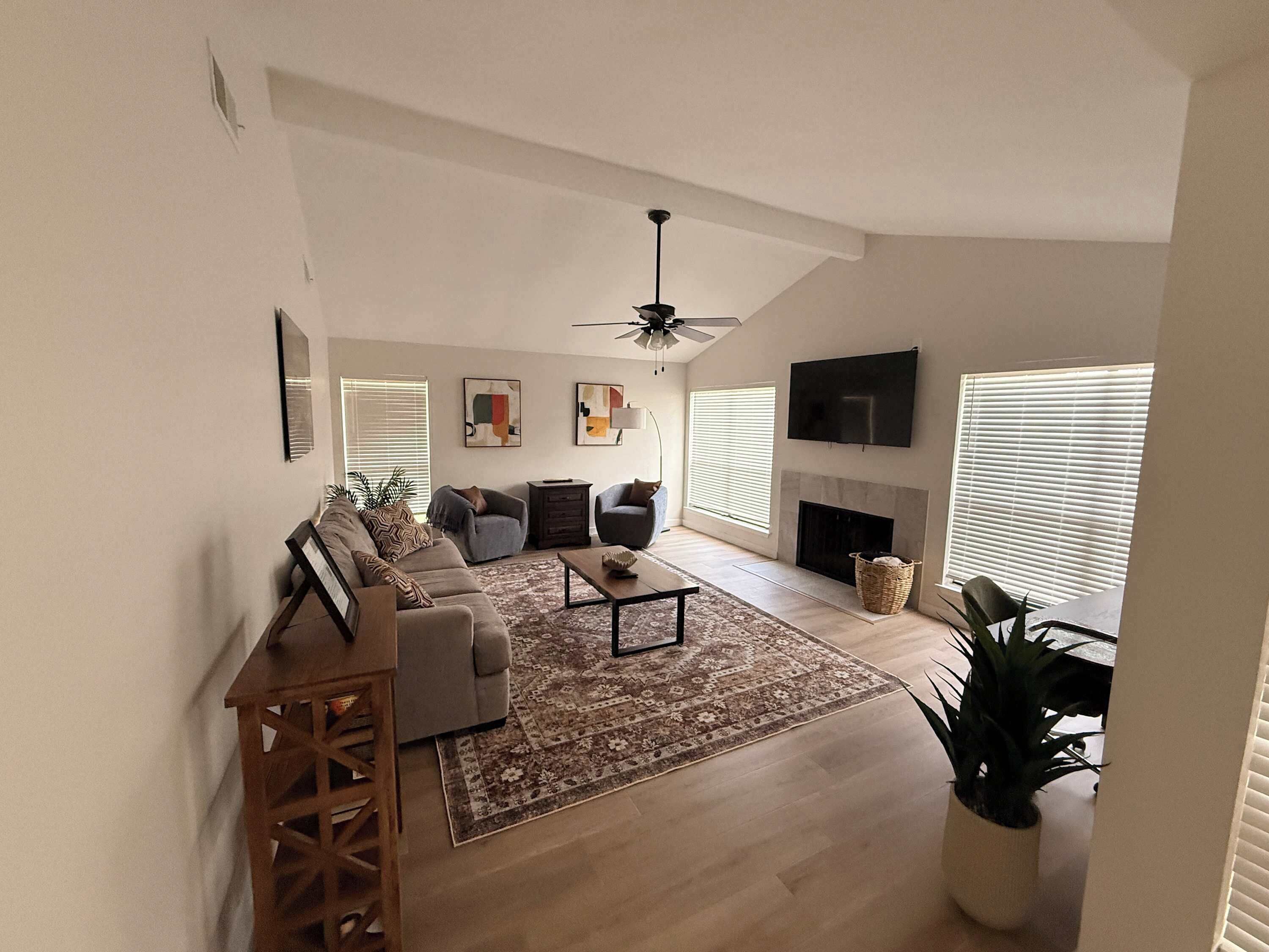 A living room with a sofa set, a coffee table, a fireplace, and a TV mounted on the wall.