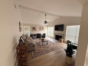 A living room with a sofa set, a coffee table, a fireplace, and a TV mounted on the wall. - Tahoka Flats, Boutique Luxury Near Trinity & Pearl (San Antonio)