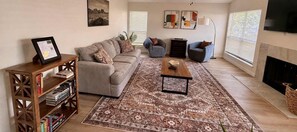 A living room with a sofa, armchairs, a coffee table, and a bookshelf. - Tahoka Flats, Boutique Luxury Near Trinity & Pearl (San Antonio)
