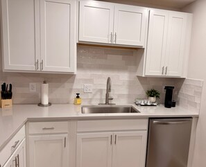 A kitchen with white cabinets, a stainless steel sink, and a coffee maker. - Tahoka Flats, Boutique Luxury Near Trinity & Pearl (San Antonio)