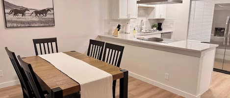 Une cuisine moderne avec des meubles blancs, un îlot central et un réfrigérateur en acier inoxydable.
