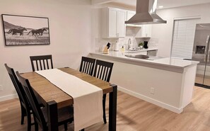 A modern kitchen with white cabinetry, a central island, and a stainless steel refrigerator. - Tahoka Flats, Boutique Luxury Near Trinity & Pearl (San Antonio)