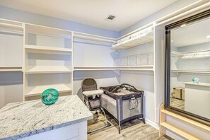 A room with built-in shelving, a changing table, and a crib. - 4BR Near Alamodome & Pearl | Sleeps 10 (San Antonio)