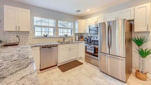 A modern kitchen with white cabinets, stainless steel appliances, and a marble countertop. - 4BR Near Alamodome & Pearl | Sleeps 10 (San Antonio)