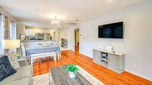 A modern living room with a dining area, a kitchen in the background, and a flat-screen TV mounted on the wall. - 4BR Near Alamodome & Pearl | Sleeps 10 (San Antonio)