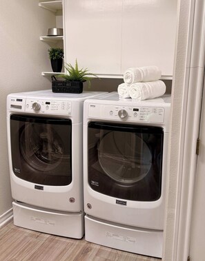 Two front-loading Maytag washing machines in a laundry room with a potted plant and folded towels on top. - 75' Amazing Lake View   Dock   Pets  Gameroom (Granite Shoals)