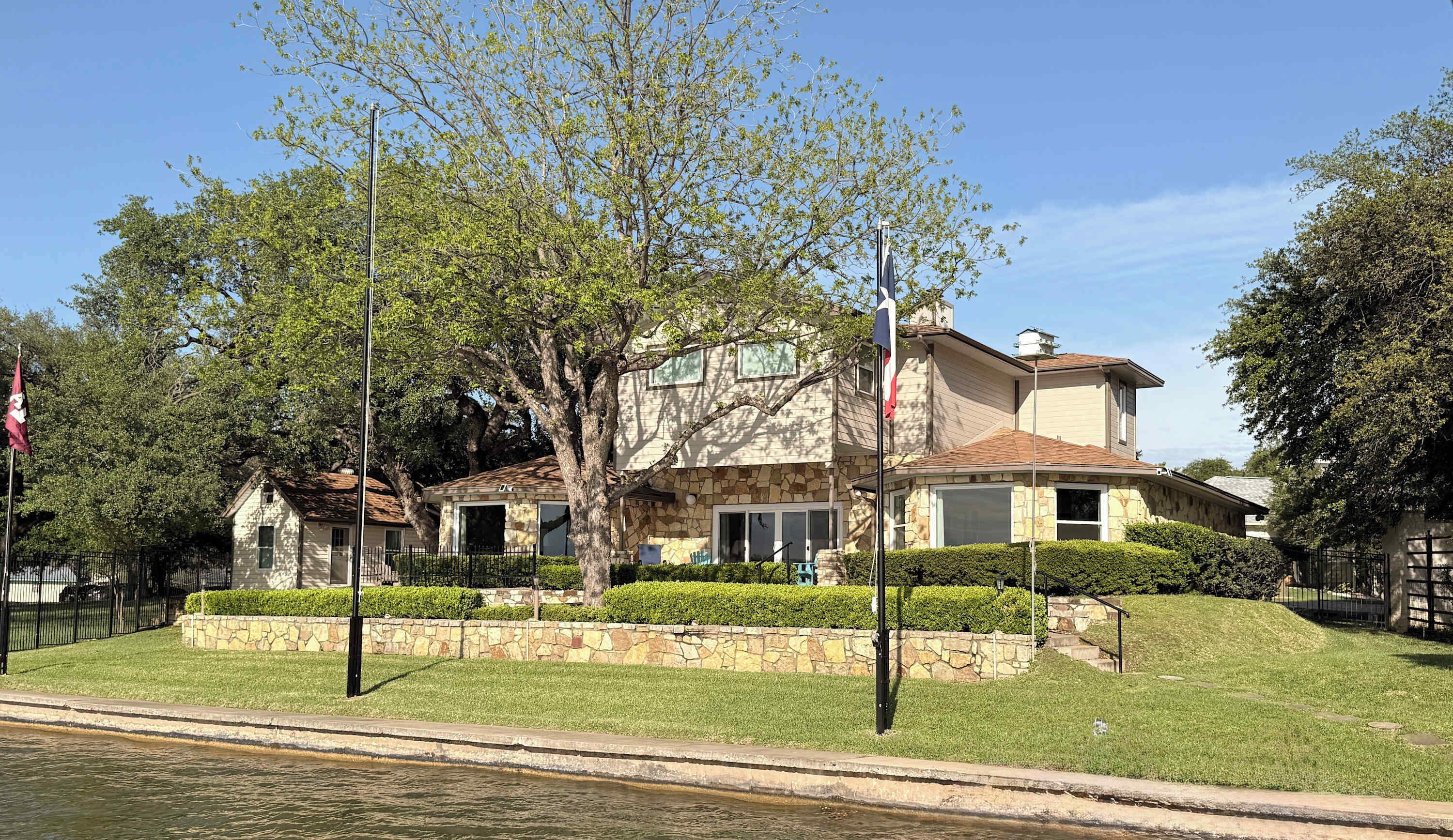 A two-story house with a stone facade, a garage, and a well-maintained lawn.