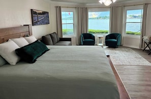 A bedroom with a large bed, two chairs, a small table, and a view of the water. - 75' Amazing Lake View   Dock   Pets  Gameroom (Granite Shoals)