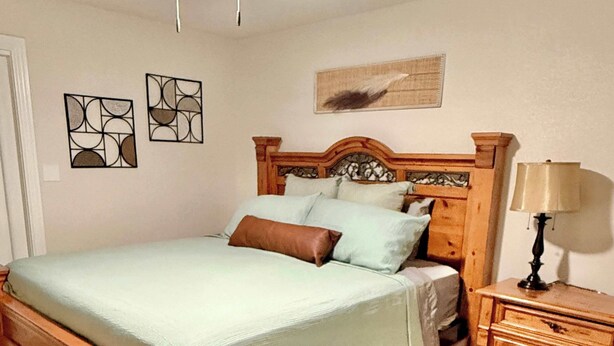 A bedroom with a wooden bed, a nightstand, a lamp, and two wall art pieces. - 75' Amazing Lake View   Dock   Pets  Gameroom (Granite Shoals)