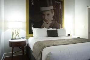 Ein Hotelzimmer mit einem Bett, einem Nachttisch mit Lampe und einem großen Bild an der Wand.