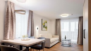 A modern living room with a dining area, a sofa, and a small table with a bottle. - Tafamunt 11 Apartment (Gaschurn)