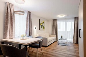 A modern living room with a dining area, a sofa, and a small table with a bottle. - Tafamunt 11 Apartment (Gaschurn)