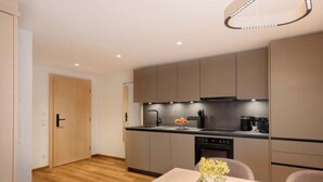 A modern kitchen with a dining area, wooden flooring, and a small table with a vase of flowers. - Tafamunt 11 Apartment (Gaschurn)