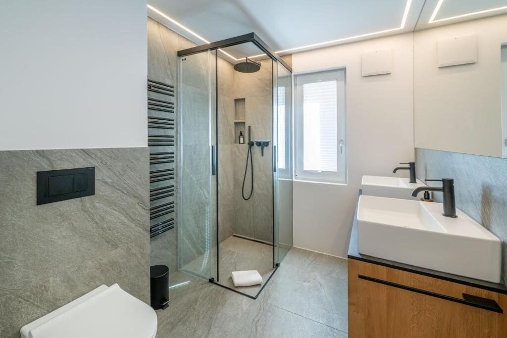 Une salle de bain moderne avec une douche à parois de verre, un lavabo blanc et un grand miroir.