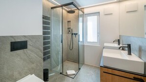 A modern bathroom with a glass-enclosed shower, a white sink, and a large mirror. - Chalet Horu - By InspiringPlaces (Zermatt)