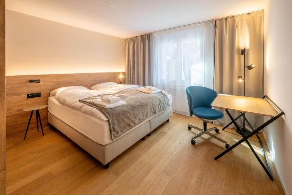 A hotel room with a bed, a desk, and a chair.